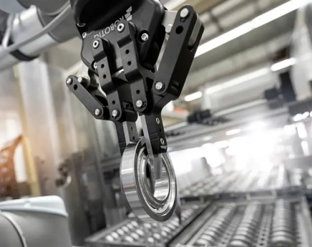 Close-up of a robotic arm grasping a bearing in a modern manufacturing facility.