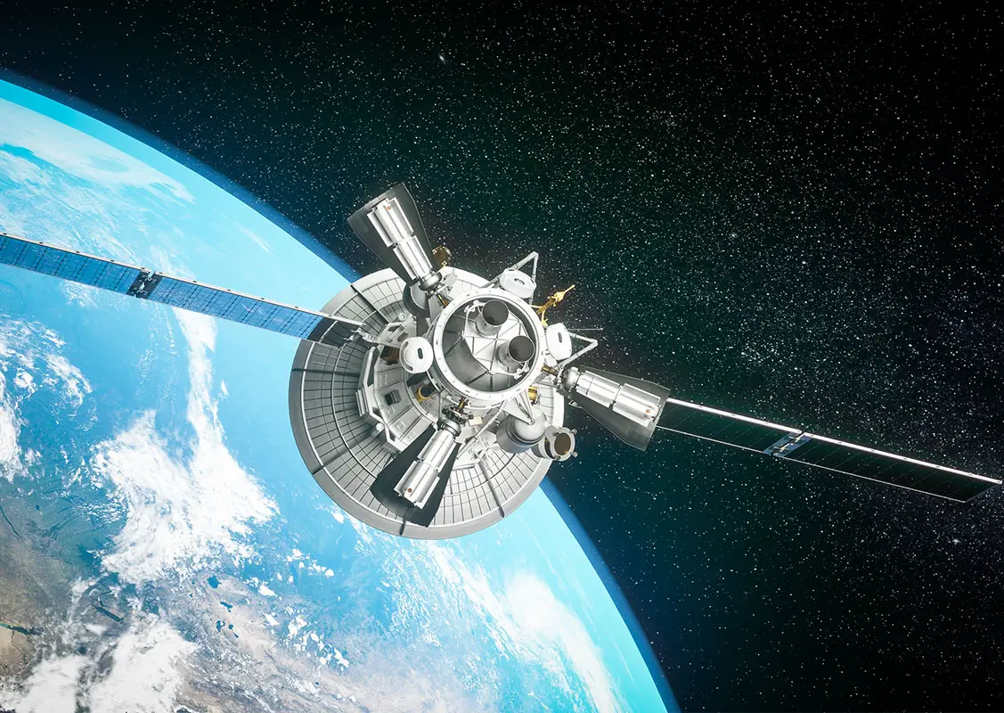 A detailed spacecraft in low Earth orbit, with extended solar panels, a circular dish and multiple instruments, with the blue curve of Earth and star-filled space visible in the background.